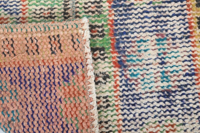 May include: Close-up of a colorful woven rug with a variety of colors, including red, blue, green, and white. The rug has a textured surface and is made of a thick, durable material.