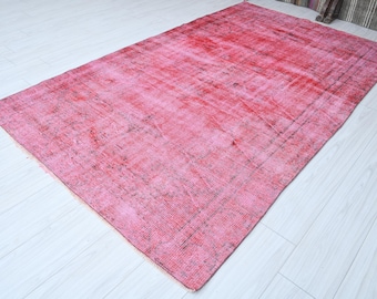 Könnte beinhalten: Ein Vintage-Teppich in Rosa und Rot mit einem verblassten Blumenmuster. Der Teppich hat einen abgenutzten Look und ist aus Wolle.