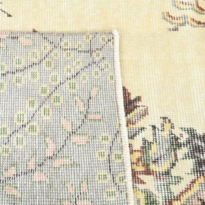 K&ouml;nnte beinhalten: Nahaufnahme eines beigen Teppichs mit Blumenmuster. Der Teppich hat einen hellgrauen Rand mit einem sich wiederholenden Muster aus kleinen Blumen. Der Teppich ist aus einem weichen, gewebten Material.
