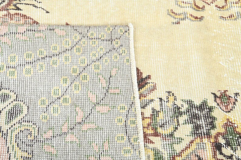 K&ouml;nnte beinhalten: Nahaufnahme eines beigen Teppichs mit Blumenmuster. Der Teppich hat einen hellgrauen Rand mit einem sich wiederholenden Muster aus kleinen Blumen. Der Teppich ist aus einem weichen, gewebten Material.