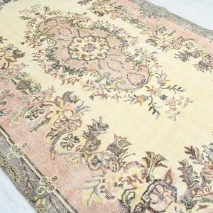 K&ouml;nnte beinhalten: Ein Vintage-Teppich mit einem floralen Muster in Rosa-, Creme- und Graut&ouml;nen. Der Teppich hat ein zentrales Medaillon mit einem sich wiederholenden floralen Design.