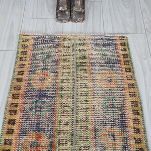 May include: A vintage style runner rug with a blue, green, and orange geometric pattern. The rug has a fringe border and is made of wool.