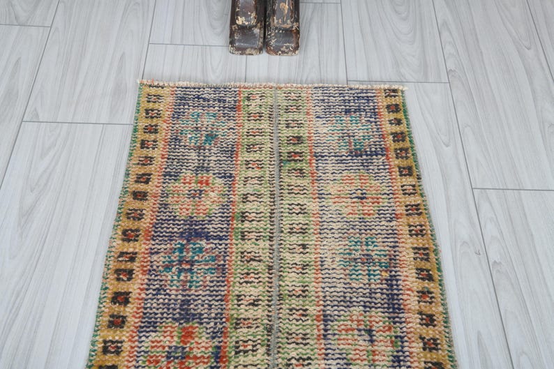 May include: A vintage style runner rug with a blue, green, and orange geometric pattern. The rug has a fringe border and is made of wool.
