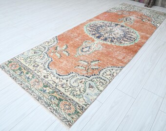 Op de afbeelding: Een vintage loper met een bloemenpatroon in tinten oranje, crème en blauw. De loper heeft een verweerde look en is perfect om een ​​bohemien touch aan je huis toe te voegen.