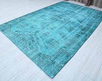 May include: A rectangular rug in turquoise and teal hues with a distressed, vintage appearance. The rug has a darker border and is placed on a light wooden floor. The rug's dimensions are visible, showcasing its colour and texture.