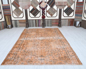 May include: A vintage-style rug with a faded orange background and a floral pattern in black. The rug has a distressed look and is perfect for adding a touch of bohemian style to any room.