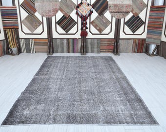 May include: A gray and white vintage rug with a distressed look. The rug has a subtle pattern and is perfect for adding a touch of rustic charm to any room.