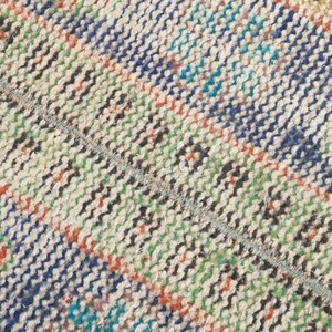 May include: Close-up of a woven rug with a multi-colored striped pattern. The rug is made of natural fibers and has a rustic, hand-crafted look.