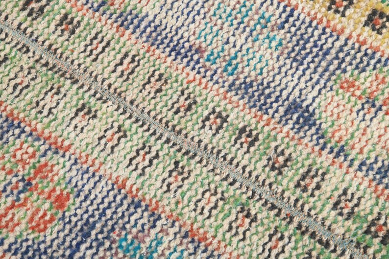 May include: Close-up of a woven rug with a multi-colored striped pattern. The rug is made of natural fibers and has a rustic, hand-crafted look.
