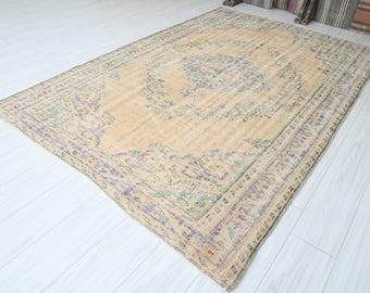 Può includere: Un tappeto vintage con sfondo beige e un motivo floreale in tonalità di viola, verde e giallo. Il tappeto ha un aspetto vissuto ed è perfetto per aggiungere un tocco di stile bohémien a qualsiasi stanza.