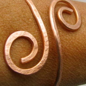 May include: A copper wire bracelet with a double spiral design. The bracelet is open and adjustable.