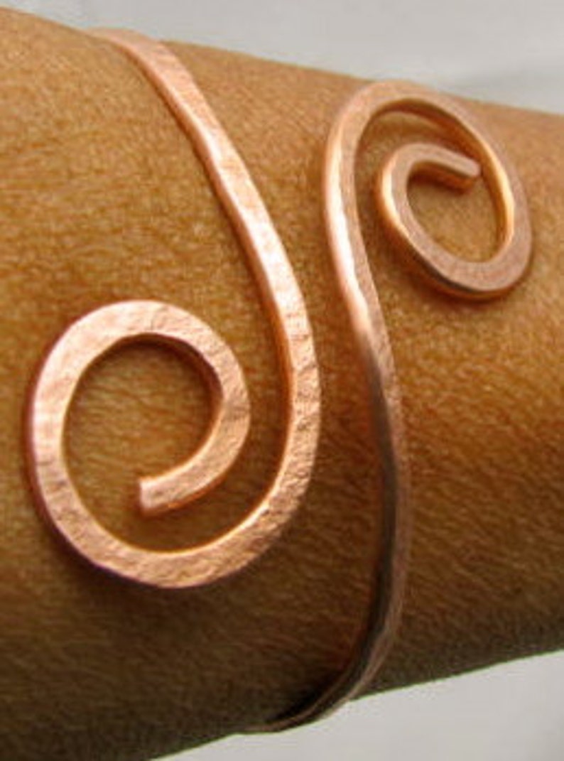 May include: A copper wire bracelet with a double spiral design. The bracelet is open and adjustable.