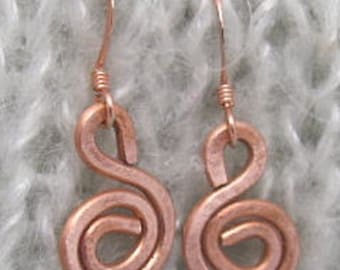 May include: A pair of copper earrings with a spiral design. The earrings are a light copper color and have a simple, elegant design.