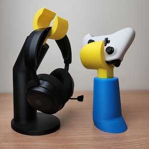 Puede incluir: Un soporte de auriculares negro con un soporte de auriculares amarillo y un soporte de mando azul con un soporte de mando amarillo.