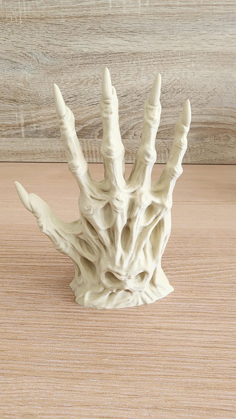 Peut inclure: Sculpture en r&eacute;sine blanc cass&eacute; repr&eacute;sentant une main squelettique ouverte. Les doigts sont longs et pointus, avec des d&eacute;tails osseux et une texture marqu&eacute;e. L'aspect vieilli sugg&egrave;re un objet ancien ou d'&eacute;poque. Id&eacute;al pour une d&eacute;coration d'Halloween.