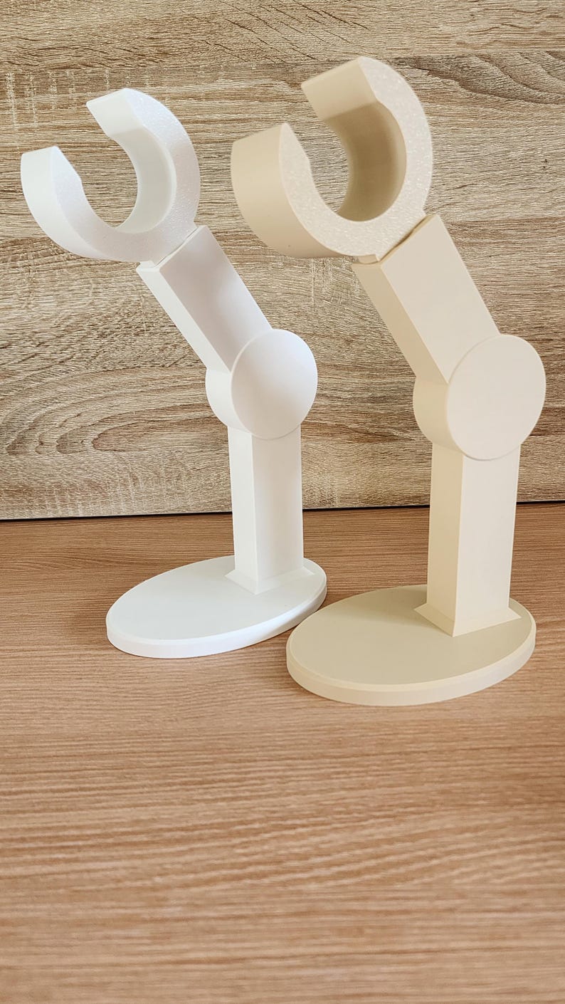 May include: Two 3D printed articulated arms, one white and one beige, with a rounded base. The arms are designed to resemble a robotic arm.