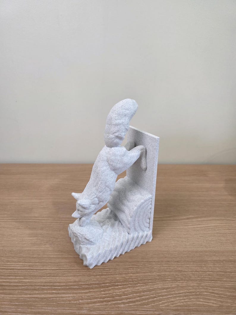 Op de afbeelding: Een lichtgrijze sculptuur van een vos die op een boomstam en een rechthoekige structuur klimt. De vos is gedetailleerd met getextureerde vacht en is gepositioneerd alsof hij actief klimt. De sculptuur staat op een houten oppervlak.