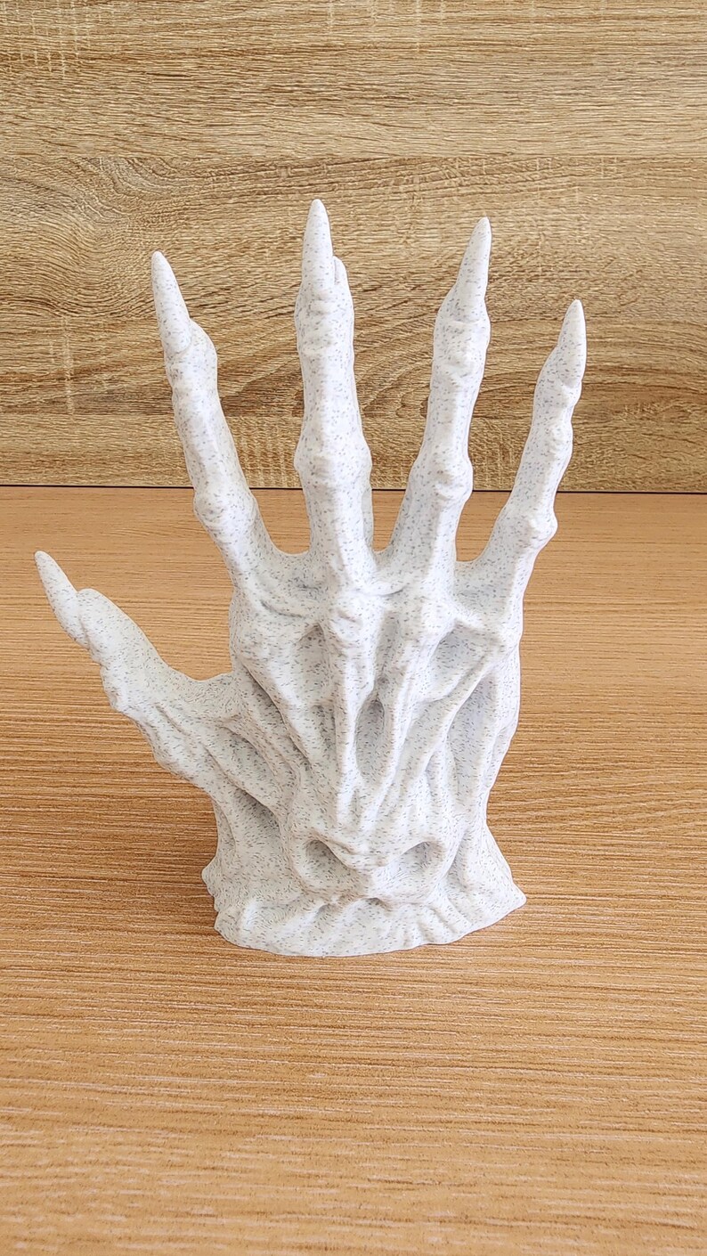 Peut inclure: Sculpture d'une main ouverte et d&eacute;taill&eacute;e, avec une finition blanche tachet&eacute;e et textur&eacute;e. Les doigts sont longs et pointus, et le design g&eacute;n&eacute;ral a une esth&eacute;tique squelettique et gothique. C'est un objet d&eacute;coratif.