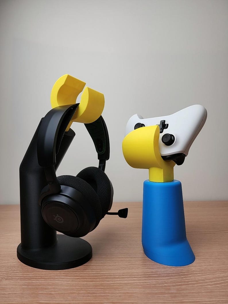 May include: A black headset stand with a yellow headset holder and a blue controller stand with a yellow controller holder.