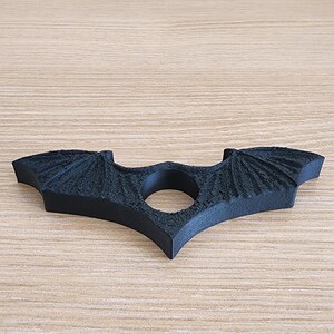 May include: A black plastic bat-shaped ring holder with a textured surface.