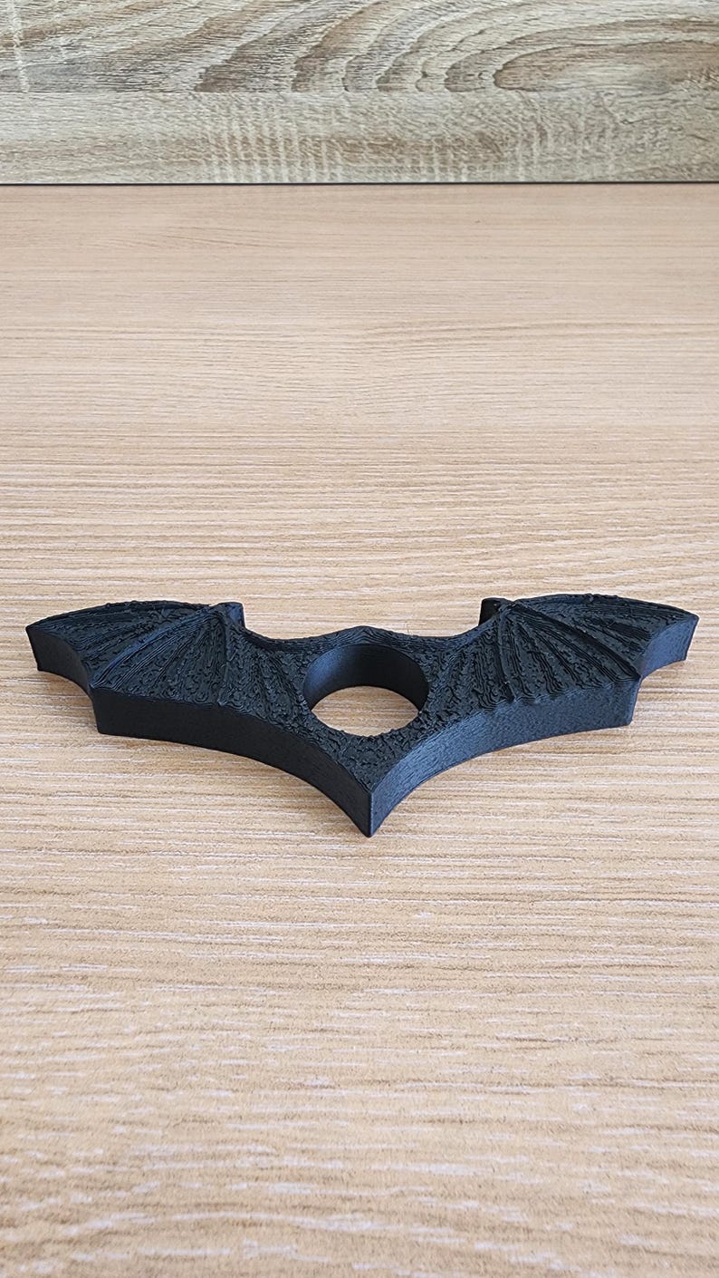 May include: A black plastic bat-shaped ring holder with a textured surface.