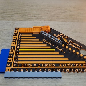 Black and orrange brick measuring ruler with some lego pieces on and around the ruler, Showing how it works.