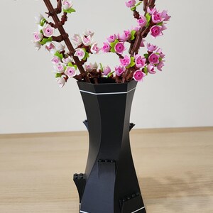 Black and White LEGO-Compatible Vase holding pink LEGO cherry blossom stems on wooden surface