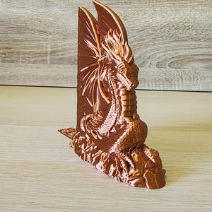 Single copper dragon bookend with wings outstretched on rustic wood backdrop