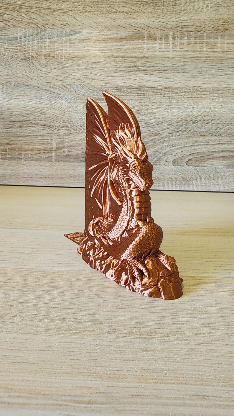 Single copper dragon bookend with wings outstretched on rustic wood backdrop