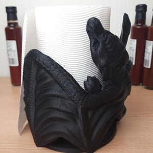 May include: Black 3D printed paper towel holder shaped like a dragon holding a roll of white paper towels.