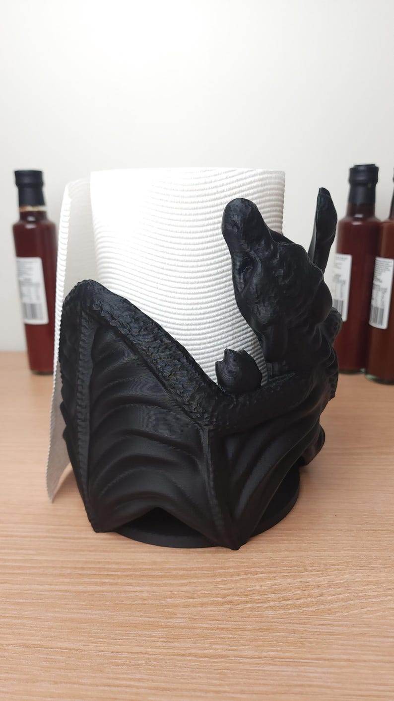 May include: Black 3D printed paper towel holder shaped like a dragon holding a roll of white paper towels.