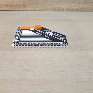 Black and White brick ruler with a brick separator attached showing the side view.