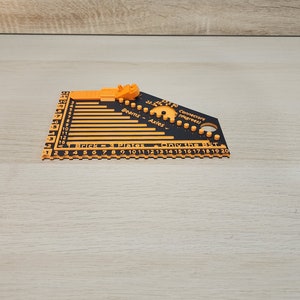 Black and orange brick ruler with a brick separator attached showing the side view.