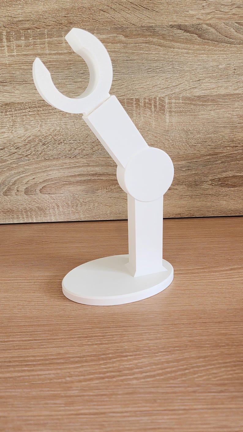 May include: White plastic phone stand with a curved arm and a round base.