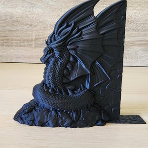 Peut inclure: Un serre-livres en forme de dragon noir avec les ailes d&eacute;ploy&eacute;es, perch&eacute; sur une base rocheuse. Le dragon est tourn&eacute; vers la gauche et pr&eacute;sente une surface textur&eacute;e et d&eacute;taill&eacute;e.