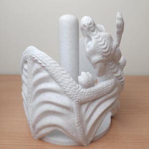 May include: White ceramic dragon paper towel holder. The dragon is curled around a central cylinder, with its wings forming the base of the holder.