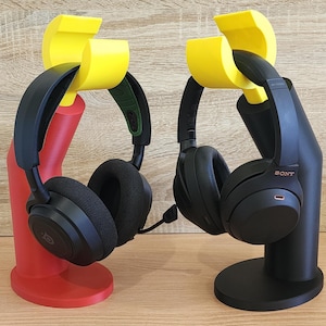 May include: Two black headphone stands with yellow and red bases. The headphones are black with a silver logo that says "SONY".