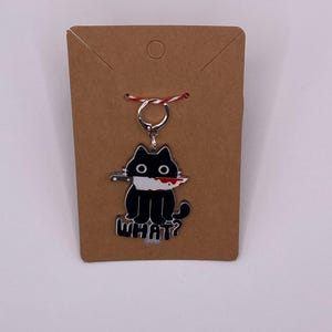May include: Black cat keychain with a bloody knife in its mouth and the word "WHAT?" underneath.