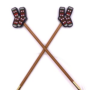 May include: A pair of bamboo circular knitting needles with gold tips and sock-shaped end caps. The sock end caps are red, green, white, and blue.