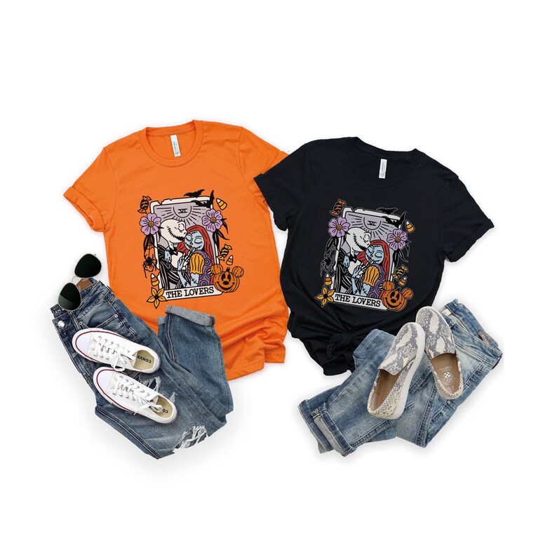 Pu&ograve; includere: Due t-shirt con una stampa grafica di Jack Skellington e Sally di The Nightmare Before Christmas. La grafica &egrave; una carta dei tarocchi con il testo "The Lovers". Una t-shirt &egrave; arancione e l'altra &egrave; nera. Entrambe le t-shirt sono abbinate a jeans e scarpe.