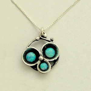 May include: A silver necklace with a pendant featuring three blue opals set in a circular design.