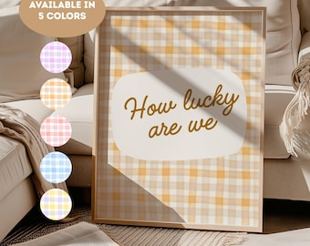 May include: A framed print with a yellow and white gingham pattern background. The print features the phrase "How lucky are we" in gold script. The image also shows a color palette of five different gingham patterns: purple, yellow, pink, blue, and yellow.