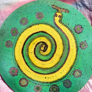 Può includere: Un pezzo decorativo rotondo dipinto a mano con un motivo a spirale giallo e verde che ricorda un serpente. L'opera d'arte è ambientata su uno sfondo verde acqua macchiato e adornata con piccoli accenti floreali nei toni del rosa e del verde.