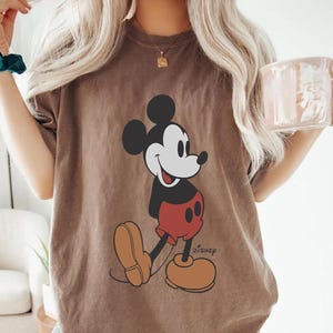 Op de afbeelding: Een oversized bruin t-shirt met een vintage Mickey Mouse-afbeelding en het woord "DISNEY" gedrukt in de rechterbenedenhoek.