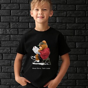 May include: A black t-shirt with a graphic of a cartoon bear wearing a baseball cap and sunglasses, sitting in a chair and reading a newspaper. The text "Read More, Talk Less" is printed below the graphic.