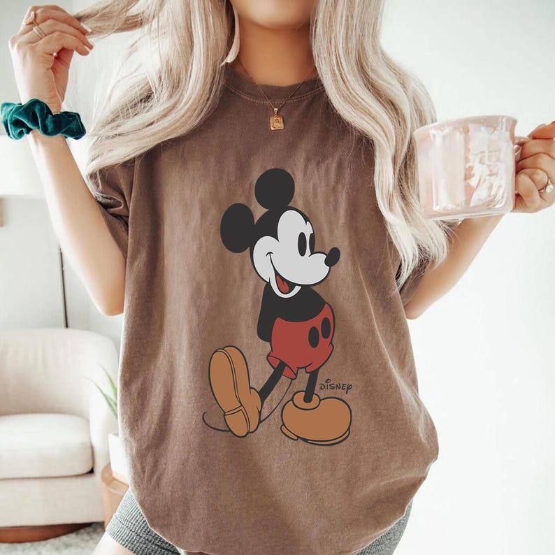 Op de afbeelding: Een oversized bruin t-shirt met een vintage Mickey Mouse-afbeelding en het woord "DISNEY" gedrukt in de rechterbenedenhoek.