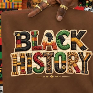 May include: A brown t-shirt with the words "BLACK HISTORY" embroidered in a vibrant, multi-coloured design. The letters are filled with patterns and colours like black, green, orange, and red. The design includes a fist and the outline of Africa.