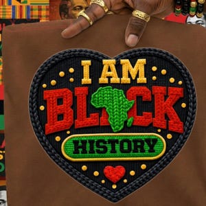Könnte beinhalten: Braunes T-Shirt mit einem herzförmigen Design. Das Design zeigt den Text "I AM BLACK HISTORY" mit einer grünen Afrika-Karte, rotem und gelbem Text und einem schwarzen Rand mit gelben Punkten. Unten befindet sich ein rotes Herz.