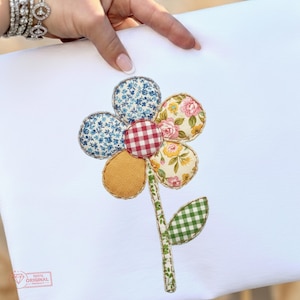 Peut inclure: Une application de fleur en tissu avec des pétales à motifs floraux bleus, vichy rouge, floral jaune et jaune uni. La tige et la feuille sont en vichy vert. La fleur est sur fond blanc.