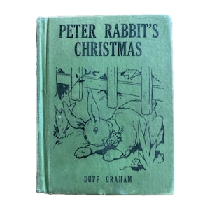 May include: A vintage copy of "Peter Rabbit's Christmas" by Duff Graham. The book has a green cover with an illustration of Peter Rabbit near a fence. The title is in black text.